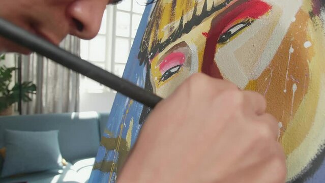 Close Up Of An Asian Artist Man Holding Paintbrush Mixed Colour And Painting A Girl'S Face On The Canvas
