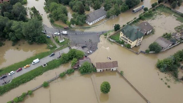 GALYCH, UKRAINE - JUNE 24, 2020: Flooded neighborhood street. Major flooding leaves city, underwater, entire community. Homes, houses overflowing water, insurance needed. Rescue teams helping people