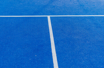 White lines of a blue paddle tennis court