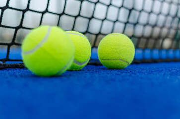 Selective focus. Three balls on a blue paddle tennis court.