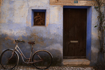 Fototapeta na wymiar Home entrance with number fifteen and blue wall with old bicycle, fragment of a typical house in an antique town in Teruel, Spain.