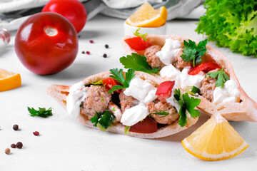 Pita pocket stuffed with meatballs and vegetables topped with sour cream and cilantro. Arabian, Turkish and Greek cuisines meal