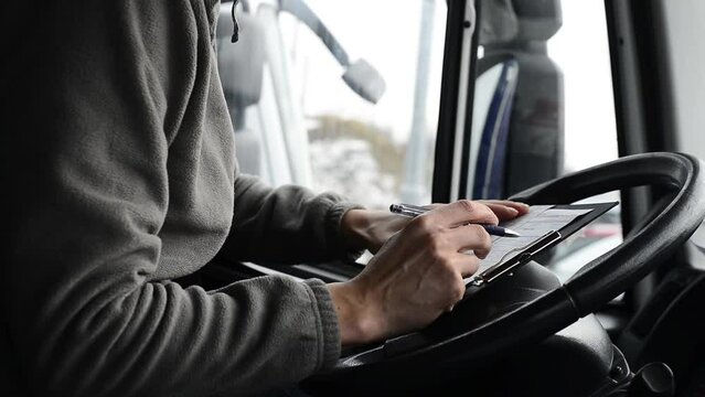 Truck driver doing his paperwork. Driver finishes his day shift in a cab.