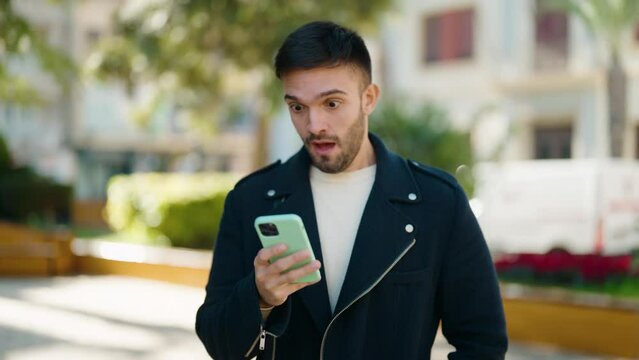 Young hispanic man using smartphone at park