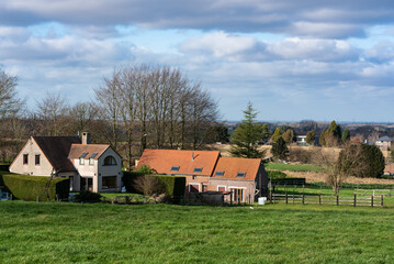 Fototapeta na wymiar Meise, Flemish Brabant Region, Belgium - 02 05 2022: View over village urbanisation and farmland with a blue sky