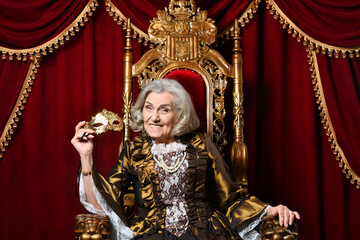 Happy beautiful senior queen with mask on throne