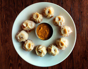Obraz na płótnie Canvas Steam-cooked momos with sauce, Nepalese Traditional Dish Momo. Steam momos on the wooden background.