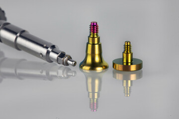 gold color dental abutment and screwdriver on white glass with creative reflection