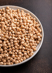 Raw dry chickpeas in plate on rustic table