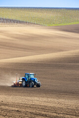 Obraz premium Tractor with seed drill in early spring landscape