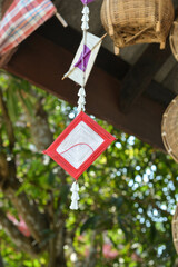 2 square knitting silky with red and white color handmade hanging on the wooden beam. And with some wicker.