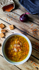 Red lentil soup in a ceramic plate on a wooden table.