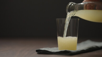 pour lemonade in tumbler glass on wood table with copy space