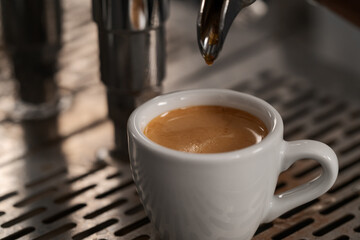 White cup with espresso on coffee machine tray