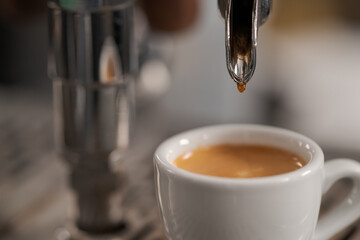 White cup with espresso on coffee machine tray