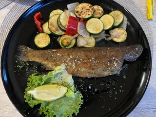 Roasted brown trout and fresh grilled vegetables, served on a plate in the restaurant of the Kamacnik picnic area (Pečena potočna pastrva i svježe povrće sa žara, servirana na tanjuru restorana)