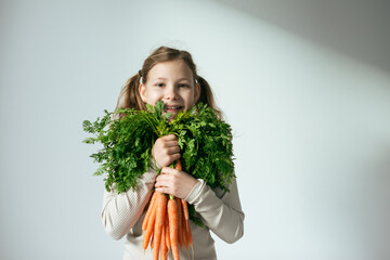 Cute smiling girl with orange carrot in studio