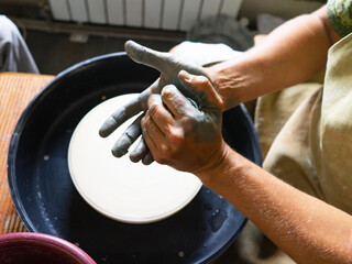 Craftsman is molding the clay into the desired shape on potter's wheel. Made ceramic products. Selective focus.