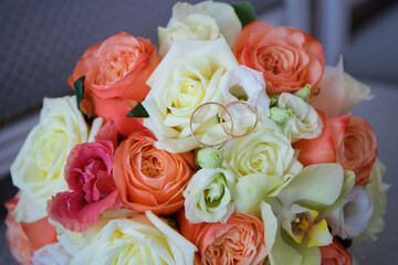 Wedding rings lie on a bouquet of roses of different colors