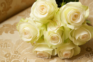 Wedding rings lie on a bouquet of roses
