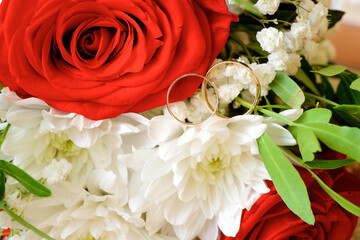 Wedding rings lie on rose and chrysanthemum flowers