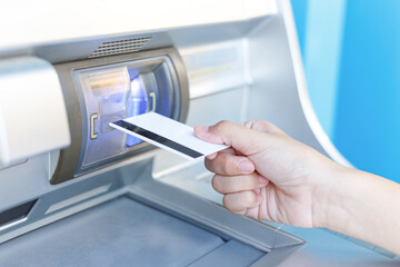 Hand of a woman inserting ATM credit card into atm machine to transfer or withdraw money
