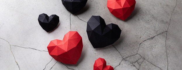 Red and black paper hearts isolated on grey cracked concrete background