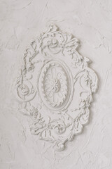 Round decorative clay stucco relief molding with floral ornaments on white ceiling in abstract classical style interior