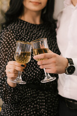 Women's and men's hands with glasses of sparkling wine on the background of the Christmas tree