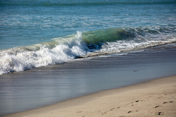 A Curling Wave Splashing onto a California Sandy Beach