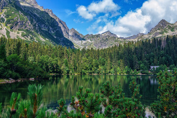 Beautiful summer landscape of High Tatras, Slovakia - Poprad lake, lush forest, mountains and white clouds on the sky