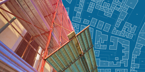 Renovation of a residential building with a metal scaffolding in a construction site - concept with an imaginary cadastral map of territory with buildings