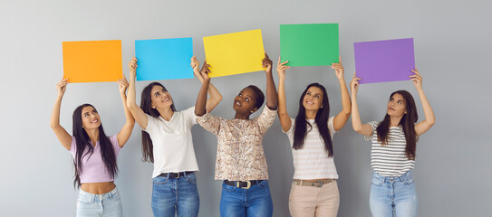 Banner background with group of happy young multiracial women looking up at colorful orange, blue,...