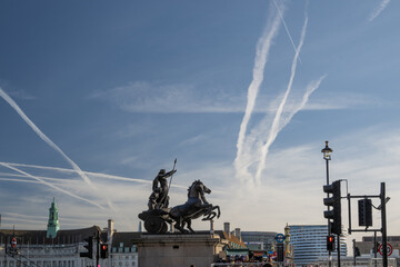 Boadicea and Her Daughters bronze statue at the Westminster Bridge under plane trails in the sky