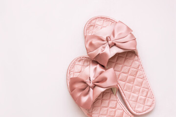 Close-up of pink satin female glamorous home slippers with bows isolated on a white background. Top view