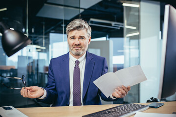 Businessman received a consolation letter, anxious and annoyed working at the computer, man at work
