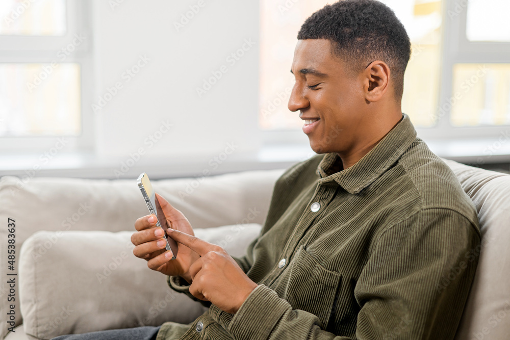 Fototapete handsome guy is using smartphone for messaging, texting. young man in smart casual wear sitting with