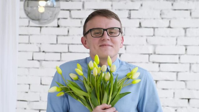 Smiling nerd with a bouquet of flowers looks at the camera. Valentines day concept, international women's day 8 march