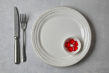 An empty white plate with cutlery and red caramel hearts