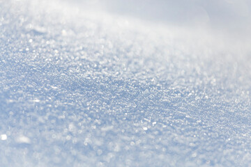 Close up macro photography texture of sparkling fresh white snow with light blue sky reflection tone. Selective focus. Winter christmas background.