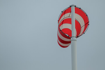 A red and white striped windsock during a Dutch storm.