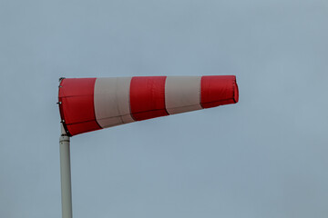 A red and white striped windsock during a Dutch storm.
