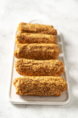 Traditional French eclairs with custard on a white ceramic serving board on a light gray culinary background. Delicious sweet cakes on the kitchen table closeup