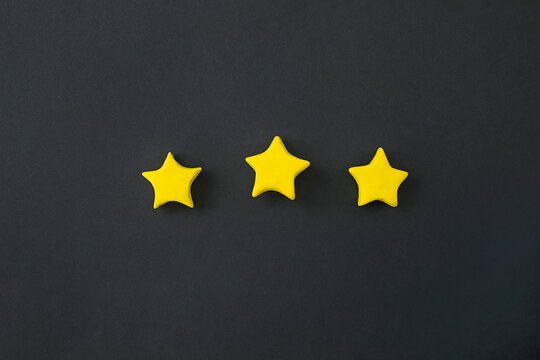Three golden star on black background. Golden star shape. Concept of top class, best quality product symbol. Sign of  evaluation, feedback from customer.