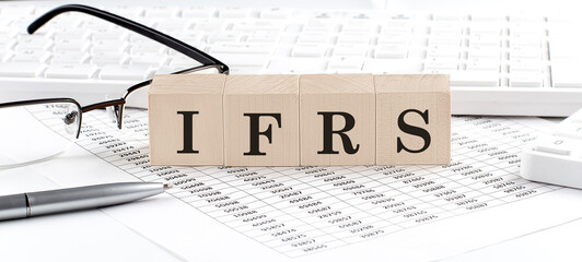 IFRS written on wooden cube with keyboard , calculator, chart,glasses.Business concept