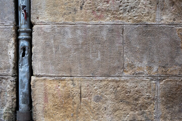 Rustic rough stone wall background with metal pipe on one side. Brown and gray stone wallpaper.
