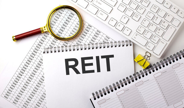 REIT Real Estate Investment Trust, text written on a notebook on chart with keyboard and planning