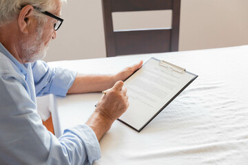 A senior retirement man sitting and concentrate reading and going to sign the contract
