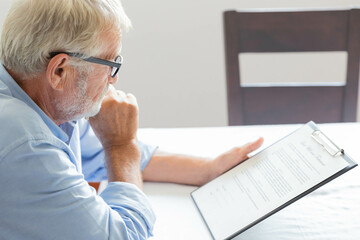 Fototapeta premium A senior retirement man sitting and concentrate reading a contract