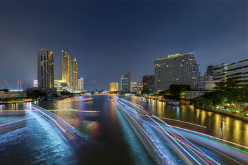 Fototapeta na wymiar Long exposure shot of river in Bangkok at night with light of boat across the river